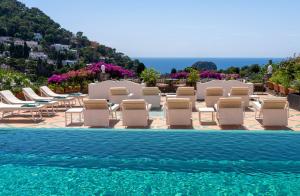 a group of lounge chairs and a swimming pool at Sina Flora in Capri