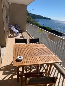 een houten tafel en stoelen op een balkon met uitzicht op de oceaan bij Le Latania in Sainte-Maxime