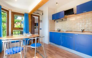 een keuken met blauwe kasten en een tafel en stoelen bij Concept Village Piccola Gardiola in San Felice del Benaco