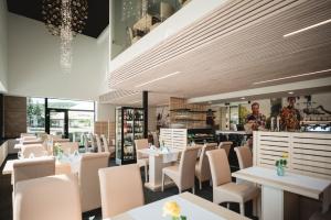 a restaurant with white tables and white chairs at Hotel Thermal ŠÍRAVA in Kaluža