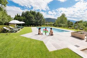 Agriturismo Al Motto في Cambiasca: ثلاثة أطفال يلعبون في العشب بجوار حمام السباحة