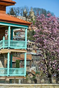 een gebouw met een balkon en een boom met paarse bloemen bij hotel Magnolia in the city centre in Koetaisi