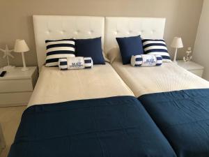 Cama grande con sábanas y almohadas azules y blancas en Dominion Beach House, en Estepona