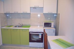 a kitchen with green and white cabinets and a sink at Apartmani Vidušin in Novalja