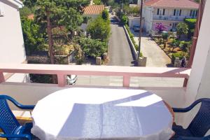 a table on a balcony with a view of a street at Apartmani Vidušin in Novalja