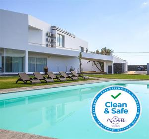 a swimming pool with chairs in front of a house at Sao Vicente Lodge - Atlantic Retreat in São Vicente Ferreira