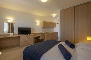a bedroom with a bed and a desk and a television at Poseidon The Beach Hotel in Budva