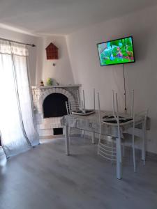- un salon avec une table et une télévision murale dans l'établissement Casa vacanze azzurra, à Montemerano