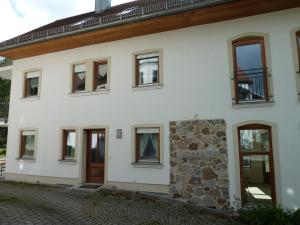 una casa bianca con finestre e un muro in pietra di Ferienwohnungen am Büchlhof im Oberpfälzer Seenland a Neunburg vorm Wald
