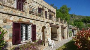 a stone house with a white chair in the yard at L'Allegra Brigata in Finale Ligure