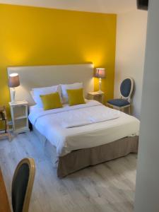 a bedroom with a large bed with yellow walls at Hôtel Au Grand Duquesne in Dieppe
