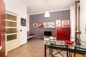 een woonkamer met een glazen tafel en een televisie bij Mercato Centrale Colorful Flat in Turijn
