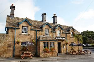 an old brick building with picnic tables and umbrellas at Devonshire Arms at Pilsley - Chatsworth in Baslow