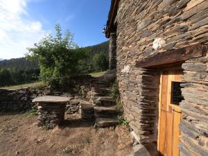 a stone building with a door and a stone wall at Bordes Pirineu, Costuix in Areu