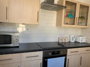 a kitchen with a stove top oven and a microwave at Delamere holiday flat in Blackpool