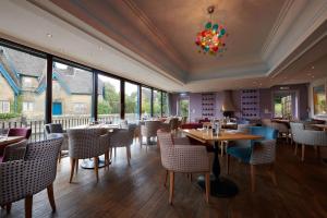 a restaurant with tables and chairs and windows at The Beeley Inn at Chatsworth in Beeley