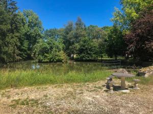 una mesa de picnic en un parque junto a un estanque en L'étang des Mirandes, en Varaignes