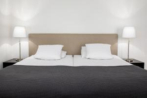 a bed with two white pillows and two lamps at Hotel Wilhelmina in Domburg