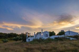 a white building in a field with a sunset at Monte das Sesmarias in Redondo