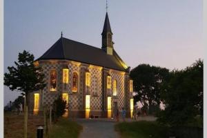 a large stone church with lights on at La cabine en Baie de Somme in Cayeux-sur-Mer