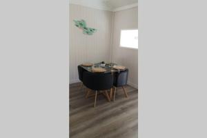 a dining room with a table and black chairs at La cabine en Baie de Somme in Cayeux-sur-Mer