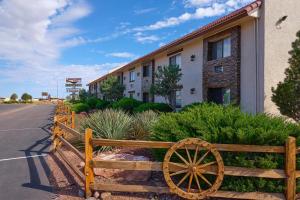 uma cerca de madeira com uma roda de madeira em frente a um edifício em Grand Canyon Inn and Motel - South Rim Entrance em Valle