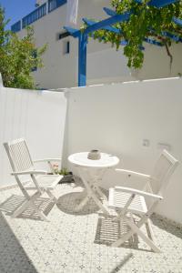 two white chairs and a table on a patio at Veletas Rooms in Adamantas