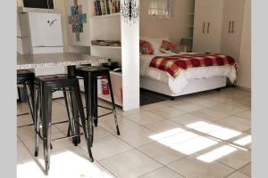 1 dormitorio con cama, mesa y taburetes en Chelmsford Cottage en Puerto Elizabeth