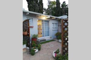 una piccola casa bianca con cancello e piante in vaso di Chelmsford Cottage a Port Elizabeth