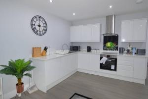 a white kitchen with a clock on the wall at Executive Central Self Contained Flat by CozyNest in Reading
