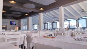 jadalnia z białymi stołami, krzesłami i oknami w obiekcie HOTELRISTORANTE IL PUNTO w mieście Marotta +19 zdjęć