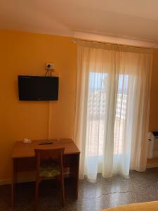 Habitación con mesa y ventana con cortinas blancas. en Hotel Ines, en Varazze