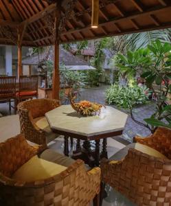 a table and chairs under a pavilion with a table and chairs at Nakula Familiar Inn in Denpasar