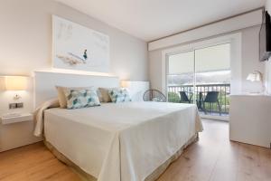 a white bedroom with a large bed and a large window at Hotel Maritim in Roses