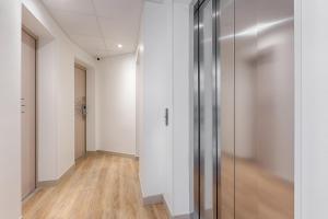 un couloir avec des murs blancs et une porte en verre dans l'établissement Hôtel Korner Etoile, à Paris