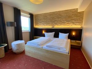 1 dormitorio con 1 cama grande con sábanas blancas en Vitalhotel Sonneneck, en Hohegeiss