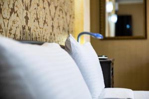 un letto con cuscini bianchi in una camera d'albergo di Vinograd Hotel a Sochi