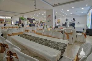 a large room with white chairs and tables and people at Hotel Mocoa Samay in Mocoa
