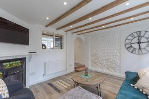 a living room with a fireplace and a clock on the wall at Lion Cottage in Holt