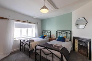 two beds in a room with a fireplace at Lion Cottage in Holt