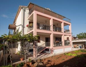 różowy apartamentowiec z balkonami i roślinami w obiekcie Apartmani Dragica w Rovinj