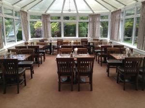 a restaurant with tables and chairs in a room with windows at Arden House Hotel in Kirkcudbright