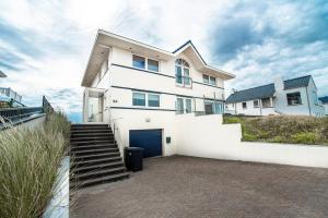 una casa blanca con una puerta y escaleras azules en Keller Beach, en Zandvoort