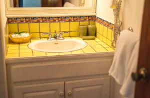 een gele betegelde badkamer met een wastafel en een spiegel bij Las Rocas Resort and Dive Center in West Bay