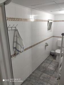 un bagno piastrellato bianco con servizi igienici e asciugamano. di Vintage Jakuzzis Vendégház a Gárdony