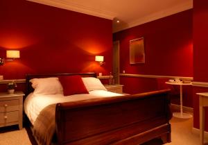 a bedroom with red walls and a bed with white sheets at The Devonshire Fell Hotel in Burnsall