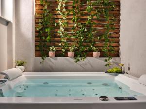 a bathroom with a tub with plants on a wall at Pothos Suites in Zakynthos Town