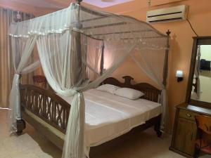 een hemelbed met witte gordijnen in een slaapkamer bij The Golden Residence in Kegalle