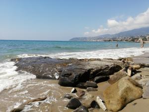 una playa con rocas y gente en el agua en Villaggio Turistico LA VESCA, en San Remo