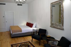 een slaapkamer met een bed, een spiegel en een stoel bij Trendy Flats Fontainhas in Porto